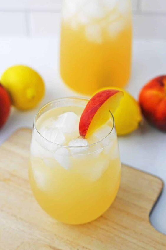 peach lemonade, peach lemonade with ice in stemless glass with slice of a peach on the side