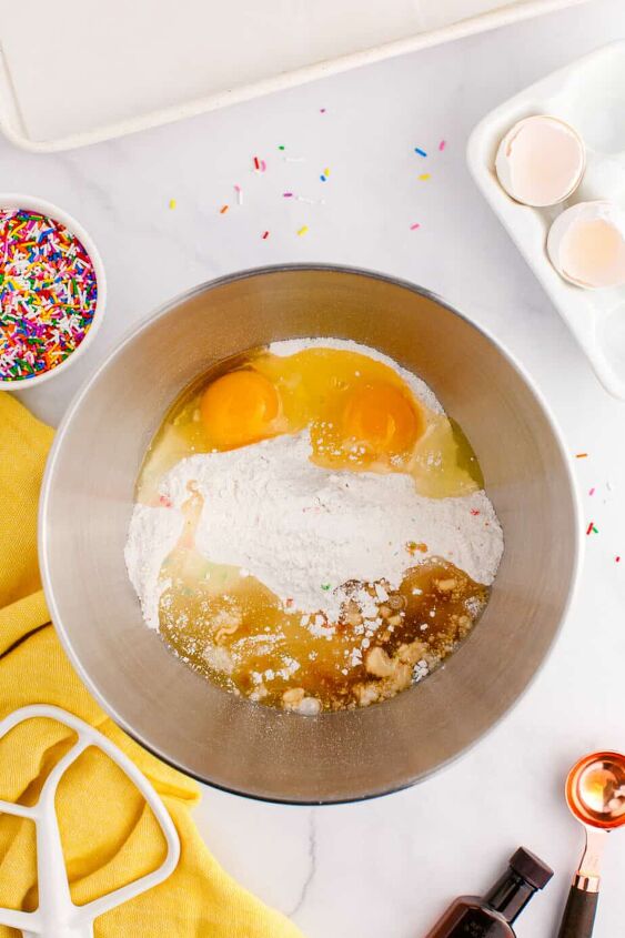 funfetti cake mix cookies, Adding wet ingredients to dry ingredients in a mixing bowl from above to mix