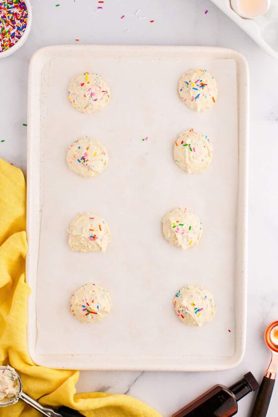 funfetti cake mix cookies, Funfetti cookie dough balls from above on a counter spaced out on a cookie sheet with extra sprinkles on top of each dough ball
