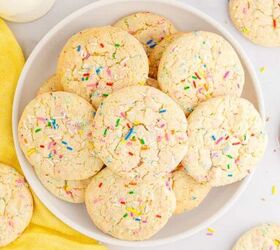 funfetti cake mix cookies, A plate of funfetti cookies with extra sprinkles on top from overhead on a table with milk and more cookies near the plate