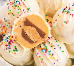 peanut butter cup stuffed truffles, A bowl filled with white chocolate peanut butter balls with one showing the peanut butter cup inside and topped with sprinkles