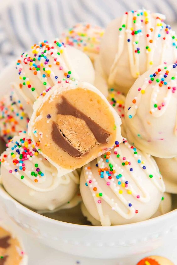 peanut butter cup stuffed truffles, A bowl filled with white chocolate peanut butter balls with one showing the peanut butter cup inside and topped with sprinkles