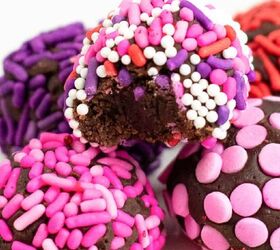 peanut butter cup stuffed truffles, Close up of brownie truffles in a small stack with one missing a bite Treats have pink red and purple sprinkles