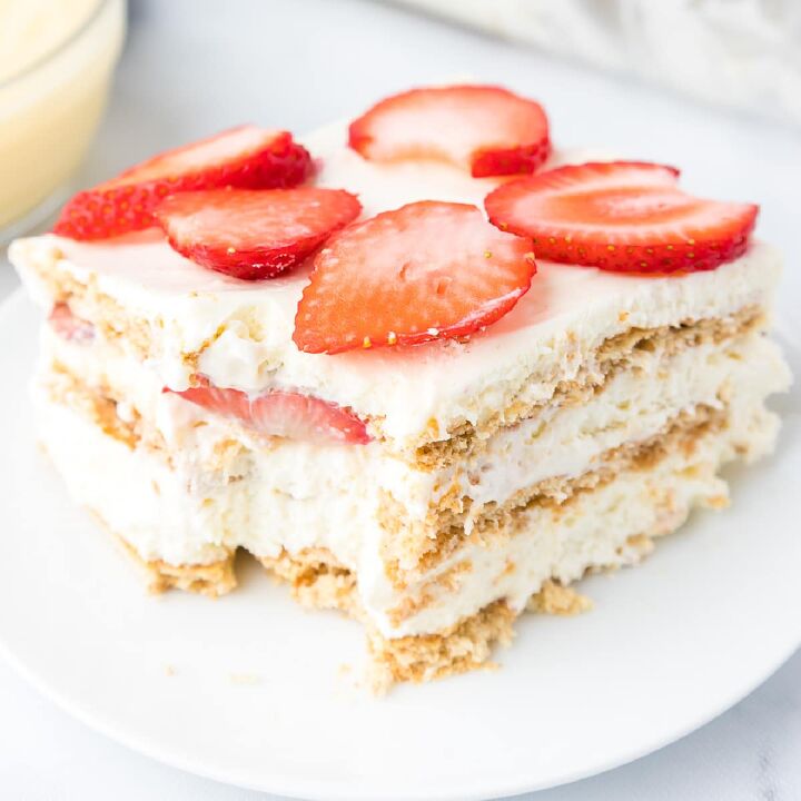 fresh strawberry cobbler, Up close view of a slice of strawberry cream cheese icebox cake on a plate missing a bite