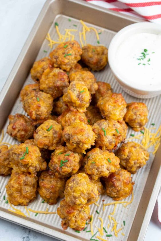 sausage and cheese balls, A pile of Bisquick sausage and cheese balls on a small baking sheet with a white bowl of dip in the corner