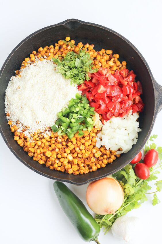 elote recipe off the cob elote corn dip, Adding diced tomatoes peppers onions and cheese to a pan of crispy corn in a skillet from overhead