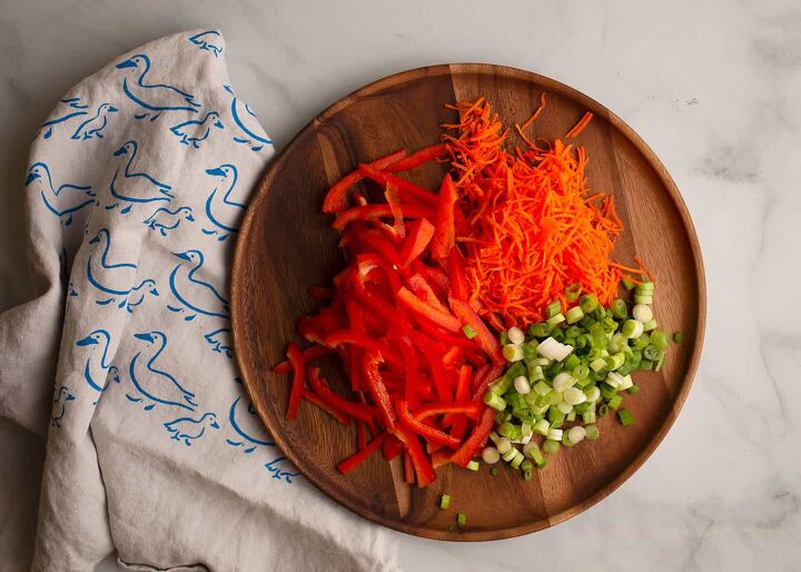 sesame noodle salad, Slivered red bell pepper grated carrots and sliced scallions on a wooden platter