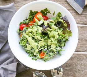keto vegan avocado dressing recipe gluten free, vegan avocado dressing recipe drizzled over a salad with micro greens and tomatoes in a white bowl with spoons and a napkin