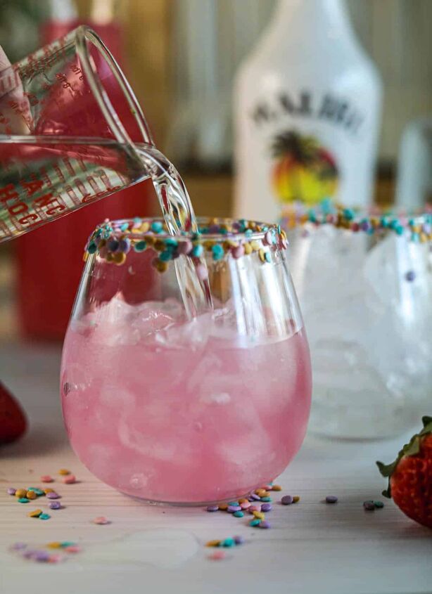 drunk bunny cocktail perfect for a grown up easter, Adding rum into glasses of pink lemonade with sprinkles on rim