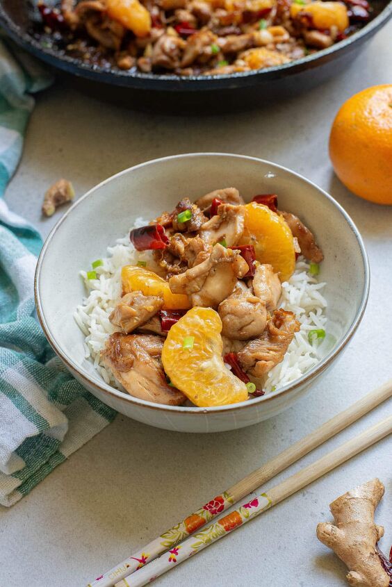 how to make easy chinese mandarin chicken, Mandarin orange chicken in a white bowl over rice and more in a cast iron pan above it