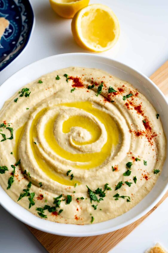easy homemade hummus recipe without garlic, Drizzling the hummus with olive oil and garnishing with paprika and parsley