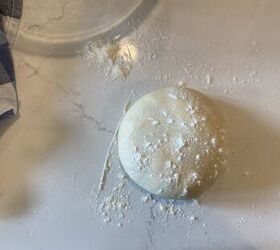 how to make the best brioche hamburger buns from scratch, a ball of dough sprinkled with flour laying on a white countertop