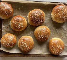 how to make the best brioche hamburger buns from scratch, homemade hamburger buns laying on a parchment paper covered baking sheet