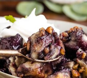 blueberry cobbler bubble up, A close up of blueberry cobbler in a bowl topped with pecans and whipped cream A spoon is lifting a portion of the dessert