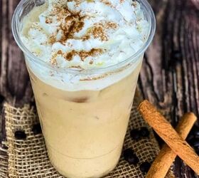 how to make the best iced coffee at home, Starbucks copycat iced pumpkin spice latte in a large glass and topped with whip cream and a sprinkle of cinnamon Two cinnamon sticks beside it with coffee beans