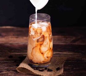 how to make the best iced coffee at home, Cream being poured into a glass with coffee and ice cubes