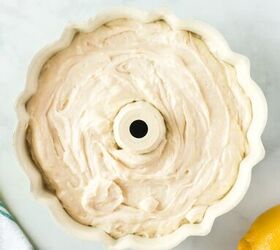 this lemon bundt cake recipe makes me happy, cake batter poured into a white bundt pan Real whole lemon on the side of bundt pan