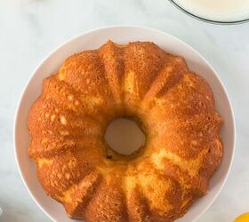 this lemon bundt cake recipe makes me happy, baked bundt pan cake on a white plate Fresh whole lemons and sliced fresh lemons on the side