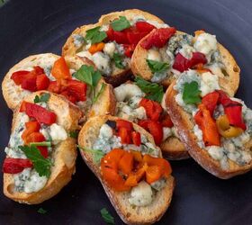 easy gorgonzola crostini with roasted red pepper, Crostini tipped with crumbled gorgonzola and roasted red peppers on a black plate