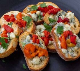 easy gorgonzola crostini with roasted red pepper, A round black plate of crostini topped with gorgonzola and roasted red pepper