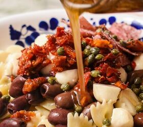 farfalle italian pasta salad, Hand pouring the homemade dressing on top of the pasta salad in a bowl