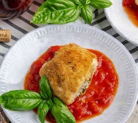 amazing chicken rollatini with spinach and sausage stuffing, A breaded chicken rollatini on a plate with tomato sauce near a bottle of wine and sprigs of basil