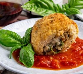 amazing chicken rollatini with spinach and sausage stuffing, A breaded chicken roll on a plate of tomato sauce with a sprig of basil