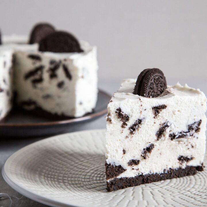 oreo cheesecake recipe cookies and cream cheesecake, A slice of oreo cheesecake on a white plate with the remaining cheesecake in the background