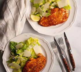 parmesan crusted chicken with caesar salad, Two plates of Parmesan Chicken Caesar Salad with shaved parmesan and lemon slices