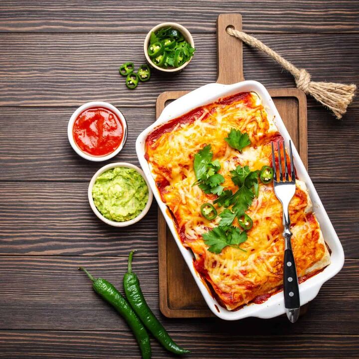 beef and bean enchiladas simple and flavorful enchilada recipe, A pan of Beef and Been Enchiladas with garnishes in bowls surrounding it