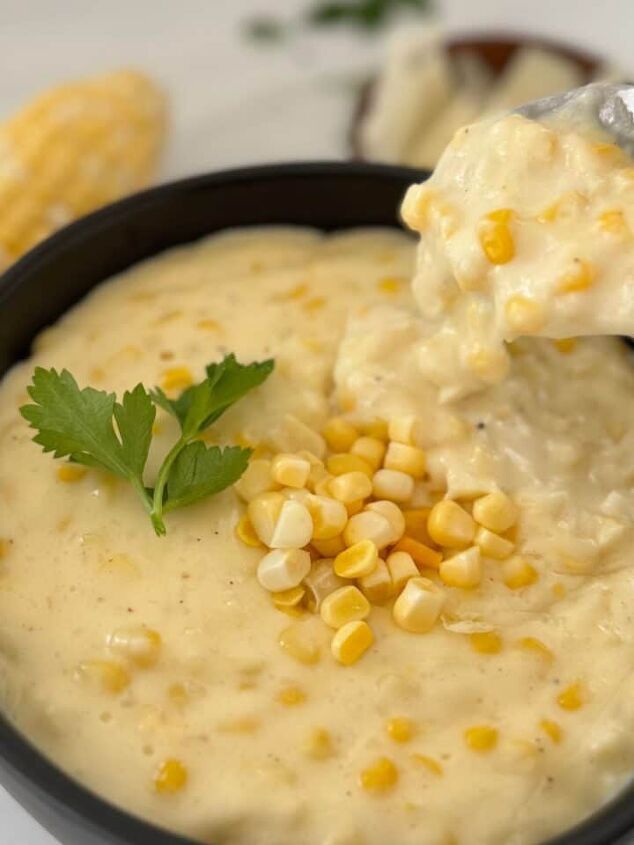 gluten free corn casserole, Gluten free creamed corn in a black bowl with someone spooning some out