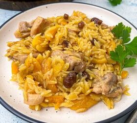 chicken orzo bake one pan family dinner, A plate of chicken orzo bake topped with tender chicken pieces raisins and garnished with a sprig of parsley The orzo is fluffy and golden complemented by hints of dried fruit creating a colorful and appetizing dish