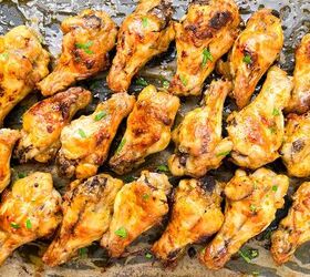 garlic butter chicken wings oven baked, A tray of golden brown roasted chicken wings garnished with fresh herbs displayed in neat rows on a lined baking sheet The wings are glistening indicating they are freshly cooked