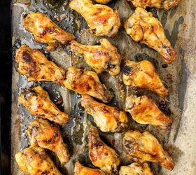 garlic butter chicken wings oven baked, A baking tray filled with neatly arranged golden brown garlic butter chicken wings rests on parchment paper with slight oil drippings visible The wings are evenly cooked showcasing crispy skin and a mouthwatering glazed exterior