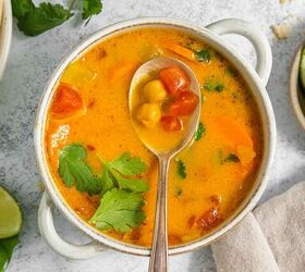 coconut curry soup, A bowl of coconut curry soup garnished with cilantro with a spoon resting on top