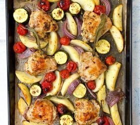 sheet pan chicken thighs and veggies, A sheet pan with roasted chicken thighs potato wedges zucchini slices cherry tomatoes and red onion segments garnished with sage leaves The dish appears golden brown and appetizingly arranged