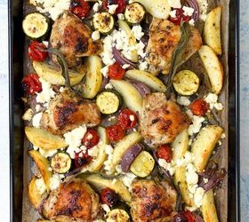 sheet pan chicken thighs and veggies, A roasted tray bake with chicken thighs potato wedges cherry tomatoes zucchini slices red onion and crumbled feta cheese The dish is garnished with fresh herbs baked to a golden brown on a parchment lined baking tray
