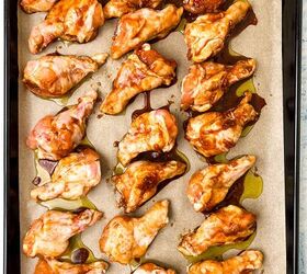 easy soy garlic chicken wings recipe, Soy garlic chicken wings coated in sauce are arranged on a parchment lined baking tray ready for cooking The wings appear marinated with a reddish glaze and are evenly spaced on the tray