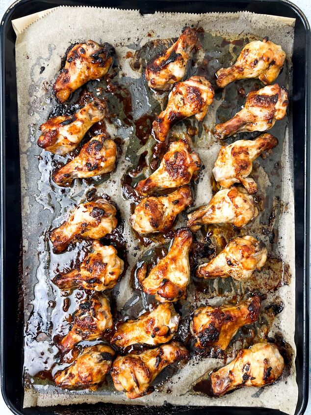 easy soy garlic chicken wings recipe, A baking tray filled with evenly spaced golden brown soy garlic chicken wings on parchment paper with visible caramelization and savory juices