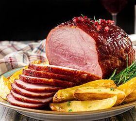 the 3 ingredient ham glaze recipe that changes everything, A glazed sliced ham garnished with fresh rosemary is served on a plate with golden potato wedges A checkered cloth and a beverage in the background add to the rustic table setting