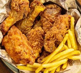 how to make buttermilk fried chicken, The image shows a basket containing pieces of crispy fried chicken alongside golden fries all placed on printed paper