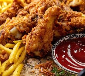 how to make buttermilk fried chicken, A platter of crispy fried chicken wings and golden French fries is served with a side of ketchup in a decorative bowl The dish is garnished with a small sprig of herbs