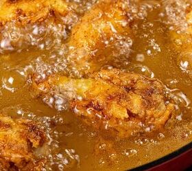 how to make buttermilk fried chicken, Close up of golden brown chicken pieces frying in bubbling hot oil creating a crispy texture The chicken is partially submerged with visible sizzling indicating the cooking process in progress The oil glistens under the light enhancing the appetizing scene