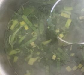 lemony green goddess chicken rice soup avgolemono style, taking a cup of broth with greens herbs from soup pot to add to blender