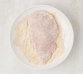 parmesan lemon chicken, chicken dredged in flour mixture in a white dish