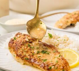 parmesan lemon chicken, chicken on a white plate with rice and a spoon shown drizzling sauce over chicken