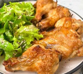 crispy salt and vinegar chicken wings recipe, A plate with crispy baked chicken wings and a side of fresh green salad garnished with grated cheese A gray napkin is placed next to the plate set on a light blue background