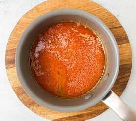 crispy salt and vinegar chicken wings recipe, A saucepan filled with rich bubbly salt and vinegar marinade sits on a round wooden cutting board The sauce appears to be thick with visible textures on the surface suggesting a simmering or reduction process