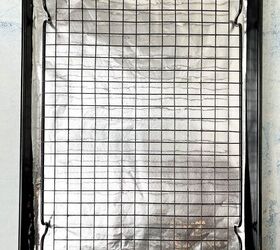 crispy salt and vinegar chicken wings recipe, A baking tray lined with aluminum foil topped with a black wire cooling rack The tray is set on a light blue surface