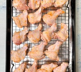 crispy salt and vinegar chicken wings recipe, Raw marinated chicken drumsticks coated with a light seasoning arranged on a wire rack over a baking sheet lined with foil The setup is on a light colored surface